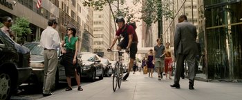 Movie still from “Premium Rush” (2012), directed by David Koepp – A man riding a bike down the middle of a street; Wide shot, Low angle