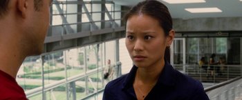 Movie still from “Premium Rush” (2012), directed by David Koepp – A woman standing in front of a window looking sad; Close Up shot, Over the shoulder angle