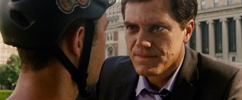 Movie still from “Premium Rush” (2012), directed by David Koepp – A man in a suit and a bicycle helmet is looking at another man in a suit; Close Up shot, Over the shoulder angle