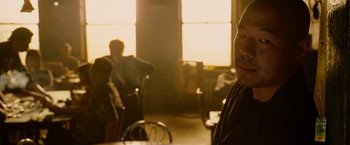 Movie still from “Premium Rush” (2012), directed by David Koepp – A man sitting at a table in front of a window; Close Up shot, Over the shoulder angle