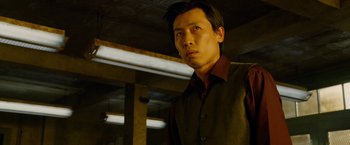 Movie still from “Premium Rush” (2012), directed by David Koepp – A man standing in a dark room wearing a vest; Close Up shot, Low angle