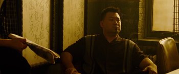 Movie still from “Premium Rush” (2012), directed by David Koepp – A man sitting in front of a wall; Medium shot, Low angle