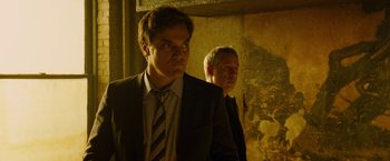 Movie still from “Premium Rush” (2012), directed by David Koepp – A man in a suit and tie standing next to another man in a suit and tie; Close Up shot, Low angle