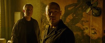 Movie still from “Premium Rush” (2012), directed by David Koepp – A man standing next to another man in front of a wall; Close Up shot, Low angle