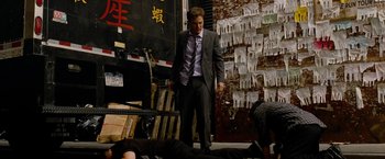 Movie still from “Premium Rush” (2012), directed by David Koepp – A man in a business suit standing next to a man laying on the ground; Wide shot, High angle