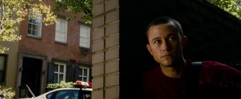 Movie still from “Premium Rush” (2012), directed by David Koepp – A person standing next to a brick wall; Close Up shot, Over the shoulder angle