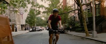 Movie still from “Premium Rush” (2012), directed by David Koepp – A man riding a bike down a street; Wide shot, High angle