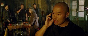 Movie still from “Premium Rush” (2012), directed by David Koepp – A man talking on a cell phone in front of a group of people; Medium shot, Over the shoulder angle