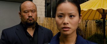 Movie still from “Premium Rush” (2012), directed by David Koepp – A man and a woman standing next to each other in front of a fence; Close Up shot, Over the shoulder angle
