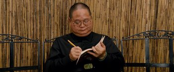 Movie still from “Premium Rush” (2012), directed by David Koepp – A man in a black shirt is writing on a piece of paper; Close Up shot, Low angle