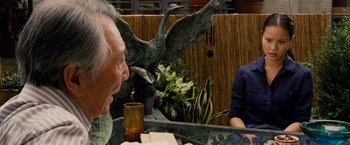 Movie still from “Premium Rush” (2012), directed by David Koepp – A man sitting at a table with a glass of wine; Medium shot, Over the shoulder angle