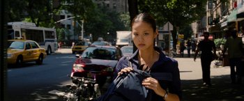 Movie still from “Premium Rush” (2012), directed by David Koepp – A woman holding a backpack on the side of the street; Close Up shot, Over the shoulder angle