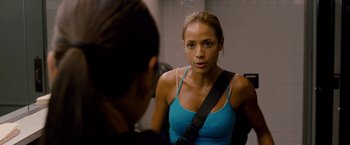 Movie still from “Premium Rush” (2012), directed by David Koepp – A woman looking into a mirror while wearing a blue shirt; Close Up shot, Over the shoulder angle