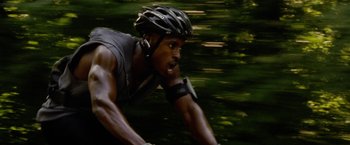 Movie still from “Premium Rush” (2012), directed by David Koepp – A man riding a bike in the woods wearing a helmet; Close Up shot, Low angle