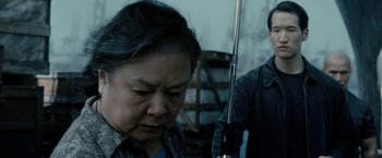 Movie still from “Premium Rush” (2012), directed by David Koepp – An older woman is looking down at a man; Close Up shot, Over the shoulder angle
