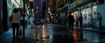 Movie still from “Premium Rush” (2012), directed by David Koepp – People walking on the sidewalk in a city at night; Extreme Wide shot, High angle