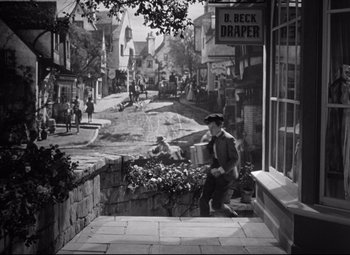 Movie still from “Pride and Prejudice” (1940), directed by Robert Z. Leonard – An old black and white photo of a man sitting on steps; Extreme Wide shot, High angle