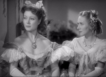 Movie still from “Pride and Prejudice” (1940), directed by Robert Z. Leonard – Two women dressed in old fashion clothing sitting next to each other; Medium shot, Over the shoulder angle