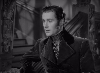 Movie still from “Pride and Prejudice” (1940), directed by Robert Z. Leonard – A black and white photo of a man in a suit and tie; Close Up shot, Over the shoulder angle