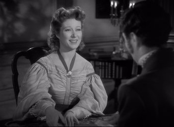 Movie still from “Pride and Prejudice” (1940), directed by Robert Z. Leonard – An old photo of a woman sitting at a table talking to a man; Medium shot, Over the shoulder angle