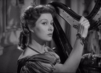 Movie still from “Pride and Prejudice” (1940), directed by Robert Z. Leonard – A beautiful woman holding a harp while standing next to a building; Close Up shot, Low angle