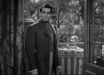 Movie still from “Pride and Prejudice” (1940), directed by Robert Z. Leonard – A black and white photo of a man standing in front of a window; Medium shot, Over the shoulder angle