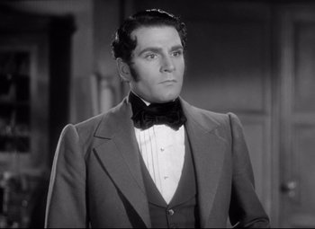 Movie still from “Pride and Prejudice” (1940), directed by Robert Z. Leonard – A black and white photo of a man wearing a suit and bow tie; Close Up shot, Low angle