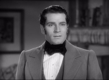 Movie still from “Pride and Prejudice” (1940), directed by Robert Z. Leonard – A black and white photo of a man wearing a suit and bow tie; Close Up shot, Over the shoulder angle