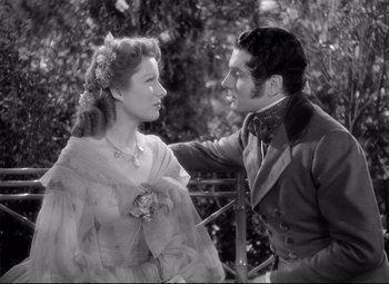 Movie still from “Pride and Prejudice” (1940), directed by Robert Z. Leonard – A man and a woman standing next to each other in front of trees; Medium shot, High angle