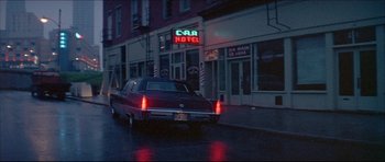 Movie still from “Prime Cut” (1972), directed by Michael Ritchie – A car driving down a street next to a building; Wide shot, Low angle