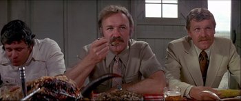 Movie still from “Prime Cut” (1972), directed by Michael Ritchie – A man sitting at a dinner table eating food; Close Up shot, Low angle