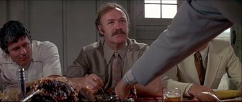 Movie still from “Prime Cut” (1972), directed by Michael Ritchie – A man sitting at a table with food in front of him; Medium shot, Over the shoulder angle