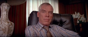 Movie still from “Prime Cut” (1972), directed by Michael Ritchie – An older man sitting in a chair wearing a tie; Close Up shot, Low angle