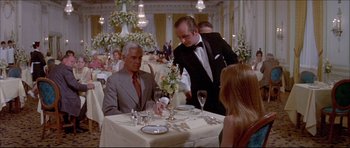 Movie still from “Prime Cut” (1972), directed by Michael Ritchie – A man sitting at a dinner table with a woman; Medium shot, Over the shoulder angle