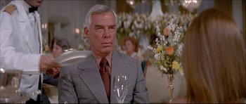 Movie still from “Prime Cut” (1972), directed by Michael Ritchie – An older man sitting in a chair holding a wine glass; Close Up shot, Over the shoulder angle
