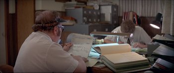 Movie still from “Prime Cut” (1972), directed by Michael Ritchie – A man sitting at a table looking at papers; Medium shot, Over the shoulder angle