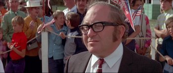 Movie still from “Prime Cut” (1972), directed by Michael Ritchie – An older man in a suit and tie with glasses; Close Up shot, Low angle