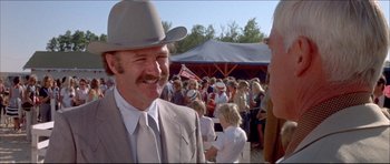 Movie still from “Prime Cut” (1972), directed by Michael Ritchie – A man in a cowboy hat is smiling for the camera; Close Up shot, Over the shoulder angle
