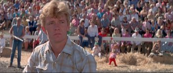 Movie still from “Prime Cut” (1972), directed by Michael Ritchie – A man in plaid shirt in front of a group of people in bleachers; Close Up shot, Low angle