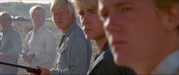 Movie still from “Prime Cut” (1972), directed by Michael Ritchie – A group of young men standing next to each other on top of a hill; Close Up shot, Low angle
