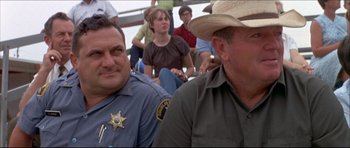 Movie still from “Prime Cut” (1972), directed by Michael Ritchie – A couple of men sitting next to each other on a bench; Medium shot, High angle