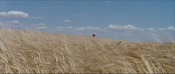 Movie still from “Prime Cut” (1972), directed by Michael Ritchie – A red truck is driving through a field of wheat; Extreme Wide shot, Low angle