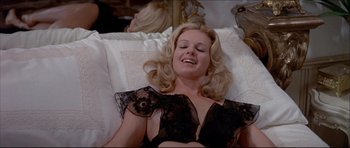 Movie still from “Prime Cut” (1972), directed by Michael Ritchie – A woman laying in a bed wearing a black bra; Medium shot, High angle