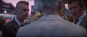 Movie still from “Prime Cut” (1972), directed by Michael Ritchie – Two men are talking to each other in front of a group of people; Close Up shot, Over the shoulder angle