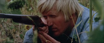 Movie still from “Prime Cut” (1972), directed by Michael Ritchie – A man with blonde hair is looking at a camera; Close Up shot, Low angle