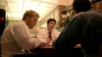 Movie still from “Primer” (2004), directed by Shane Carruth – A group of men sitting at a table in a restaurant; Medium shot, Over the shoulder angle