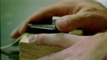 Movie still from “Primer” (2004), directed by Shane Carruth – A person holding a cell phone in their hand; Extreme Close Up shot, Overhead angle