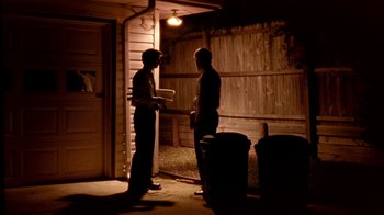 Movie still from “Primer” (2004), directed by Shane Carruth – Two men standing in the dark talking to each other; Wide shot, Over the shoulder angle