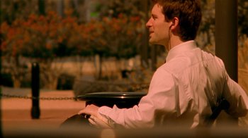Movie still from “Primer” (2004), directed by Shane Carruth – A man sitting on top of a park bench; Medium shot, Over the shoulder angle