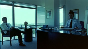 Movie still from “Primer” (2004), directed by Shane Carruth – Two people sitting at a desk in an office setting; Wide shot, High angle